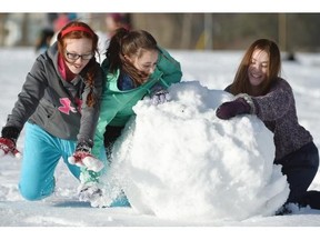 Sativa Simpson, 13 (L), Maria Lukowich, 13(C) and Kendra Akitt, 15, push some heavy snow as students in teacher Rob Schmidt’s Outdoor Pursuits class at Vimy Ridge Academy went outdoors to learn how to make snow shelters on a beautiful day in Edmonton on Monday Jan. 19, 2015.