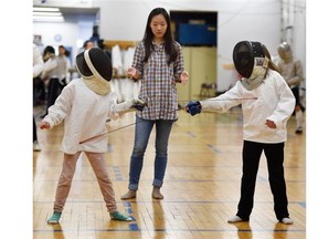 Sisters Sara Hauer, 8, left, and Melissa Hauer, 10, try out fencing with foils with instructor Ivy Lu during the Edmonton Fencing Club’s open house on Saturday, Jan. 3, 2015.