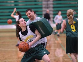 Assistant coach Drew Hanson tried to throw Tess Heinricks of balance as she moved in for a lay up. The University of Alberta Pandas basketball team practiced at Edmonton's Saville Centre on Tuesday, Jan. 13, 2015.