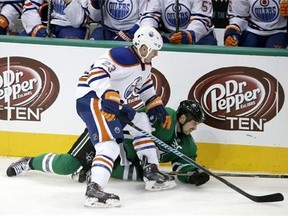 Dallas Stars' Jamie Benn (14) falls to the ice after a collision with Edmonton Oilers' Matt Hendricks (23) as the two chased a loose puck in the third period of an NHL hockey game, Tuesday, Nov. 25, 2014, in Dallas. The Stars won 3-2. (AP Photo/Tony Gutierrez)