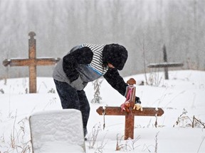 In this November 2013 photo on the Paul Band First Nation, a father visits the gravesite of his infant daughter, who died while in government care. Letter writer Debbie Faulkner says the province should act now on at least some of the recommendations it has received to prevent such deaths.