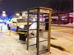 A white Dodge pickup truck allegedly involved in a pedestrian collision at 82nd Avenue and 101st Street on Thursday is seen behind some police tape and a broken phone booth at the corner of 82nd Avenue and 99th Street.