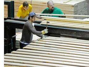 Workers cut and bundle up lumber at Spruceland Millworks in Acheson, west of Edmonton, on July 8, 2014.