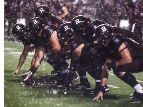 Alexander Krausnick #55 of the Ottawa Redblacks gets ready to snap the ball with the offensive line at the line of scrimmage as it rains during fourth quarter action against the BC Lions during a CFL game at TD Place Stadium on September 5, 2014 in Ottawa, Ontario, Canada.