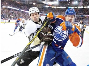 Craig Adams of the Pittsburgh Penguins checks Edmonton Oilers’ Matt Fraser into the boards during a National Hockey League game at Rexall Place on Feb. 4, 2015.