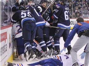 Edmonton Oilers forward Luke Gazdic lies on the ice as Winnipeg Jets defenceman Dustin Byfuglien (not shown) gets jostled along the boards after a hit during NHL action at Winnipeg’s MTS Centre on Feb. 16, 2015.