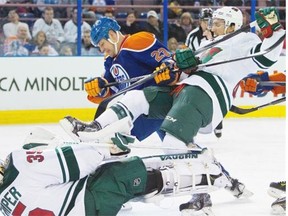 Edmonton Oilers Matt Hendricks, centre, looks for the puck as Minnesota Wild Jared Spurgeon, right, falls in front of goalie Darcy Kuemper during second period NHL action at Rexall Place in Edmonton on Thursday, Feb. 27, 2014.