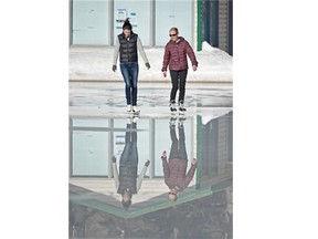 Erin Jessup, left, and Andrea Hiob skate through water on the ice surface of the Victoria Oval on a warm day in Edmonton on Monday, Feb. 23, 2015.