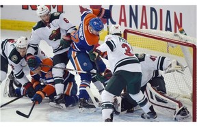 Goalie Devan Dubnyk (40) makes a save with a crowd in front of him as the Edmonton Oilers play the Minnesota Wild at Rexall Place in Edmonton on February 20, 2015.