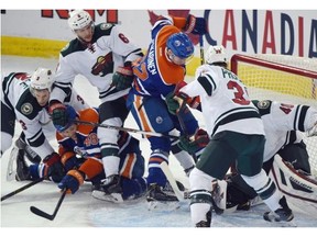 Goalie Devan Dubnyk (40) makes a save with a crowd in front of him as the Edmonton Oilers play the Minnesota Wild at Rexall Place in Edmonton on February 20, 2015.