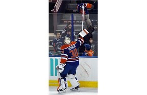 Goalie Ben Scrivens (30) picks up a jersey thrown on the ice and sends it back over the glass as the Edmonton Oilers lose 4-0 to the Minnesota Wild at Rexall Place in Edmonton on February 20, 2015.