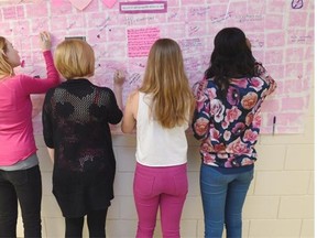 Grade 9 students (from left) Elizabeth Gauthier, Jenna Michaud, Claire Liden and Abigail Isaac participate in Pink Shirt Day by putting positive messages on a pink graffiti wall at Holy Cross Elementary/Junior High in Edmonton, February 25, 2015.