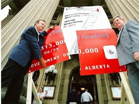 In June 1999, Alberta Treasurer Stockwell Day, left, and Premier Ralph Klein cut up a model of a giant credit card on the legislature steps to symbolize the elimination of the province’s net debt.