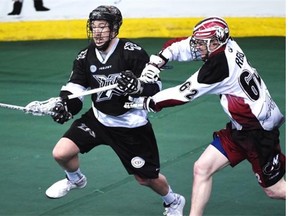 Mark Matthews of the Edmonton Rush has one hand on his stick and uses the other to fend off Creighton Reid of the Colorado Mammoth during Sunday’s National Lacrosse League game at Rexall Place.