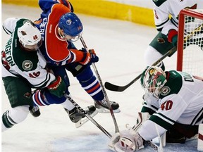 Minnesota Wild’s Jared Spurgeon upends Edmonton Oilers’ Jordan Eberle as he tries to get the puck from the glove of goalie Devan Dubnyk during NHL action on January 27, 2015 in Edmonton.