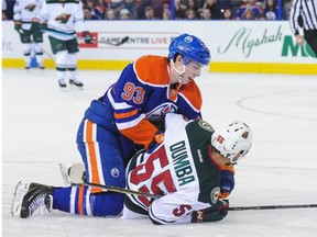 Ryan Nugent-Hopkins of the Edmonton Oilers checks his former junior teammate, Minnesota Wild defenceman Matt Dumba, to the ice during a National Hockey League game at Rexall Place on Feb. 20, 2015.