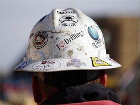 In this March 25, 2014, photo, a worker wears a protective helmet decorated with stickers during a hydraulic fracturing operation at a gas well, near Mead, Colo.