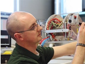 University of Alberta physics PhD student David Miles inspects the sensor for the fluxgate magnetometer he built.