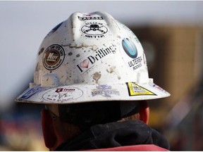 A worker wears a protective helmet decorated with stickers during a hydraulic fracturing operation at a gas well, near Mead, Colo. (AP Photo/Brennan Linsley)