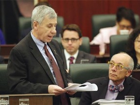 Alberta Health Minister Stephen Mandel (right) listens to Robin Campbell (left), Alberta Minister of Finance, deliver the provincial budget speech at the Alberta Legislature on March 26, 2015.