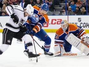 Los Angeles Kings forward Mike Richards, left, and Edmonton Oilers defenceman Andrew Ference fight for possession of the puck as Oilers goalie Ben Scrivens keeps his eyes glued on the puck during NHL action at Edmonton’s Rexall Place on Dec. 30, 2014.