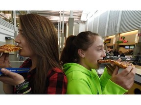 Bailey Simpson, 14(L) and Jeri-Anne Georget, 13, from Stettler Middle school, enjoyed a pizza break at the Edmonton Boat & Sportsmen’s Show in the Northland’s EXPO Centre in Edmonton on Thursday Mar. 12, 2015.