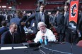 Calgary Flames GM Brad Treliving and POHO Brian Burke are photobombed by some random dude while discussing strategy at the draft table.