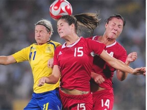 Canada’s Kara Lang (C) and Melissa Tancredi (R) head the ball with Sweden’s Victoria Svensson (L) in the women’s first round group E football match at the 2008 Beijing Olympic Games on Aug. 12, 2008.