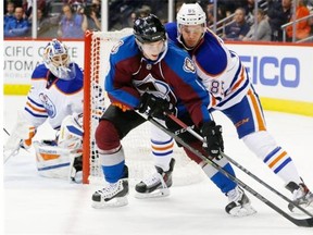 Colorado Avalanche center Matt Duchene, front left, struggles to control the puck with Edmonton Oilers defenseman Martin Marincin, front right, as goalie Richard Bachman protects the net in the first period of an NHL hockey game Monday, March 30, 2015, in Denver.
