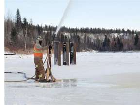 A construction worker sprays water to build up ice thickness on the Firebag River along the winter ice road from Fort McMurray to Fort Chipewyan in northern Alberta on February 4, 2015.