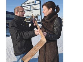 Curler Cheryl Bernard, who is doing some promotional work for Goodwill, and Lee Carleton, former owner of a 1940 Northland hockey stick, hold the venerable stick which is now headed into the Alberta Sports Hall of Fame.