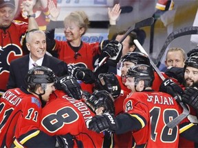 Edmonton-based ATB Financial is celebrating the Calgary Flames making the playoffs by lighting its headquarters in the NHL team’s colours. Calgary Flames’ head coach Bob Hartley, top left, celebrates Thursday with his players after an empty-net goal and 3-1 victory over the Los Angeles Kings and a trip to playoffs for the first time since 2009.