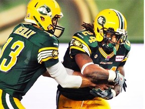 Edmonton Eskimos running back Tyler Thomas, right, takes the hand-off from quarterback Mike Reilly against the Hamilton Tiger-Cats during CFL action at Commonwealth Stadium in Edmonton, July 4, 2014.