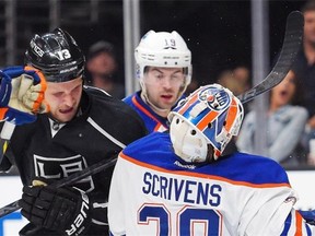 Edmonton goalie Ben Scrivens gets hit on the helmet with the stick of Los Angeles Kings left-winger Kyle Clifford as Oilers defenceman Justin Schultz watches a National Hockey League game on April 2, 2015, at Los Angeles.