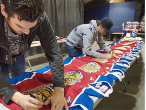 Edmonton Oil Kings winger Brandon Baddock, left, and centre Andrew Koep sign merchandice the day following the team’s playoff exit against the Brandon Wheat Kings, at Rexall Place in Edmonton, April 2, 2015.