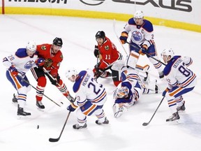 Edmonton Oilers center Matt Hendricks (23) clears the puck away from his goalie Ben Scrivens and other teammates during the second period of an NHL hockey game against the Chicago Blackhawks, Friday, March 6, 2015, in Chicago.