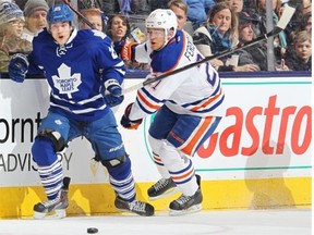 Edmonton Oilers defenceman Andrew Ference and Mike Santorelli of the Toronto Maple leafs chase after a loose puck during an NHL game at the Air Canada Centre in Toronto on Feb. 7, 2015.
