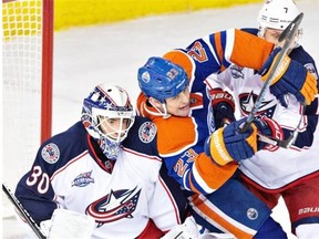 Edmonton Oilers forward Matt Hendricks gets pushed into Columbus goalie Curtis McElhinney by Blue Jackets defenceman Jack Johnson during a National Hockey League game at Rexall Place on March 18, 2015.