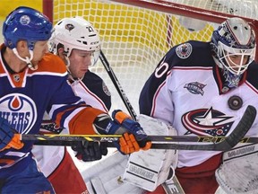 Edmonton Oilers’ Rob Klinkhammer and Columbus defenceman Ryan Murray battle for position as the puck hits Blue Jackets goalie Curtis McElhinney in the chest during Wednesday’s NHL game at Rexall Place.