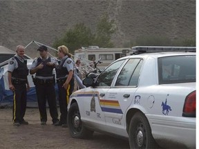 RCMP stand at the entrance to the camping area of the Boonstock Music and Art Festival in Penticton, B.C., where a 24-year-old woman from Leduc, Alberta died as the result of a drug overdose, early Saturday morning, Aug. 2, 2014. THE CANADIAN PRESS/Penticton Herald-James Miller