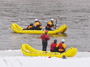 Firefighters wade into the North Saskatchewan River to be rescued by Edmonton Fire Rescue Services during swift water ice training exercise next to Rundle Park in Edmonton, March 20, 2015. Swift water ice training exercises showcase the specialized training and equipment used in ice rescue operations.