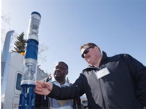 Jeff Mann (right), field specialist with Baker Hughes, shows an electric submersible pump to student Fredrick Lubwama (left) at the 10th annual Petroleum Engineering Technology industry day at NAIT on April 8, 2015, in Edmonton. Dozens of companies were on-site talking to students about career options and showcasing technologies.