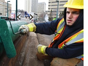 Kieran Bell of city roadway maintenance touches up the centre median metal rails along Jasper Avenue across from the Shaw Conference Centre in preparation for the Crashed Ice event starting March 12 in Edmonton, March 9, 2015.