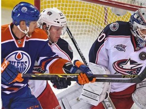 Rob Klinkhammer of the Edmonton Oilers battles for position in front of the Columbus net with Blue Jackets defenceman Ryan Murray as the puck hits goalie Curtis McElhinney (30) in the chest during Wednesday’s National Hockey League game at Rexall Place.