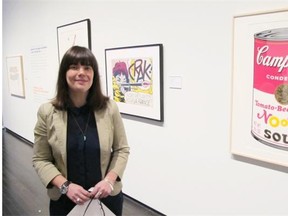 Laura Ritchie, curator of the Pop Show!, stands next to prints by Roy Lichtenstein and Andy Warhol.  T