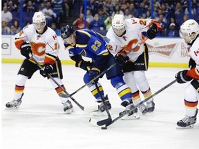 St. Louis Blues’ Dmitrij Jaskin reaches for the puck while surrounded by, from left, Johnny Gaudreau, Drew Shore and Kris Russell of the Calgary Flames during Thursday’s NHL game at St. Louis.