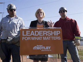 Owners of Solidarity Steel Barney Chanyi (left) and brother Timothy (right) join Alberta NDP Leader Rachel Notley as she makes a policy announcement regarding Alberta oil refinement, at Tiger Goldstick Park on April 10, 2015 in Edmonton.