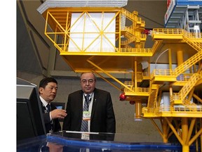 Sun Fujie (left), General Manager of Science and Technology Department, China National Offshore Oil Corporation, speaks with Alberta Energy Minister Frank Oberle (right) behind a scale model of an offshore oil rig at the World Heavy Oil Congress held at the Shaw Conference Centre in Edmonton on March 24, 2015.