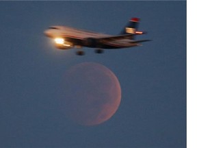 A commercial Airliner on approach to Reagan National Airport flies past the full moon during a lunar eclipse October 8, 2014 in Washington, DC.
