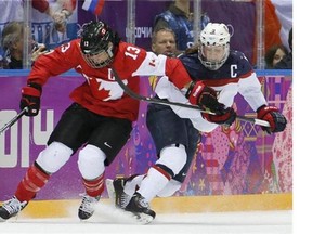 Caroline Ouellette of Canada (13) gets tangled up with Meghan Duggan of the United States (10) during the second period of the women's gold medal ice hockey game at the 2014 Winter Olympics, Thursday, Feb. 20, 2014, in Sochi, Russia. Four-time Olympian Ouellette has been added to Canada's roster for the women's world hockey championship. THE CANADIAN PRESS/ AP/Mark Humphrey